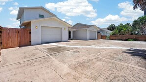A residential area with two single-story houses, each with a garage, a wooden fence, and a paved driveway. - Beautiful 4-bedroom beach front house in Ponce Inlet (Port Orange)