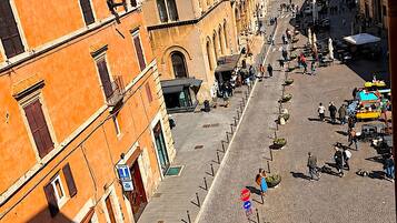 A cobblestone street with historic buildings, outdoor seating, and a clear blue sky.