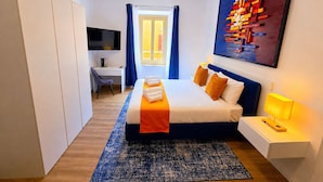 Una camera d'albergo moderna con un letto, una scrivania e un grande quadro astratto.