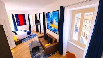 Una habitación de hotel moderna con cama, sofá, televisor y un amplio ventanal con vista a la ciudad.