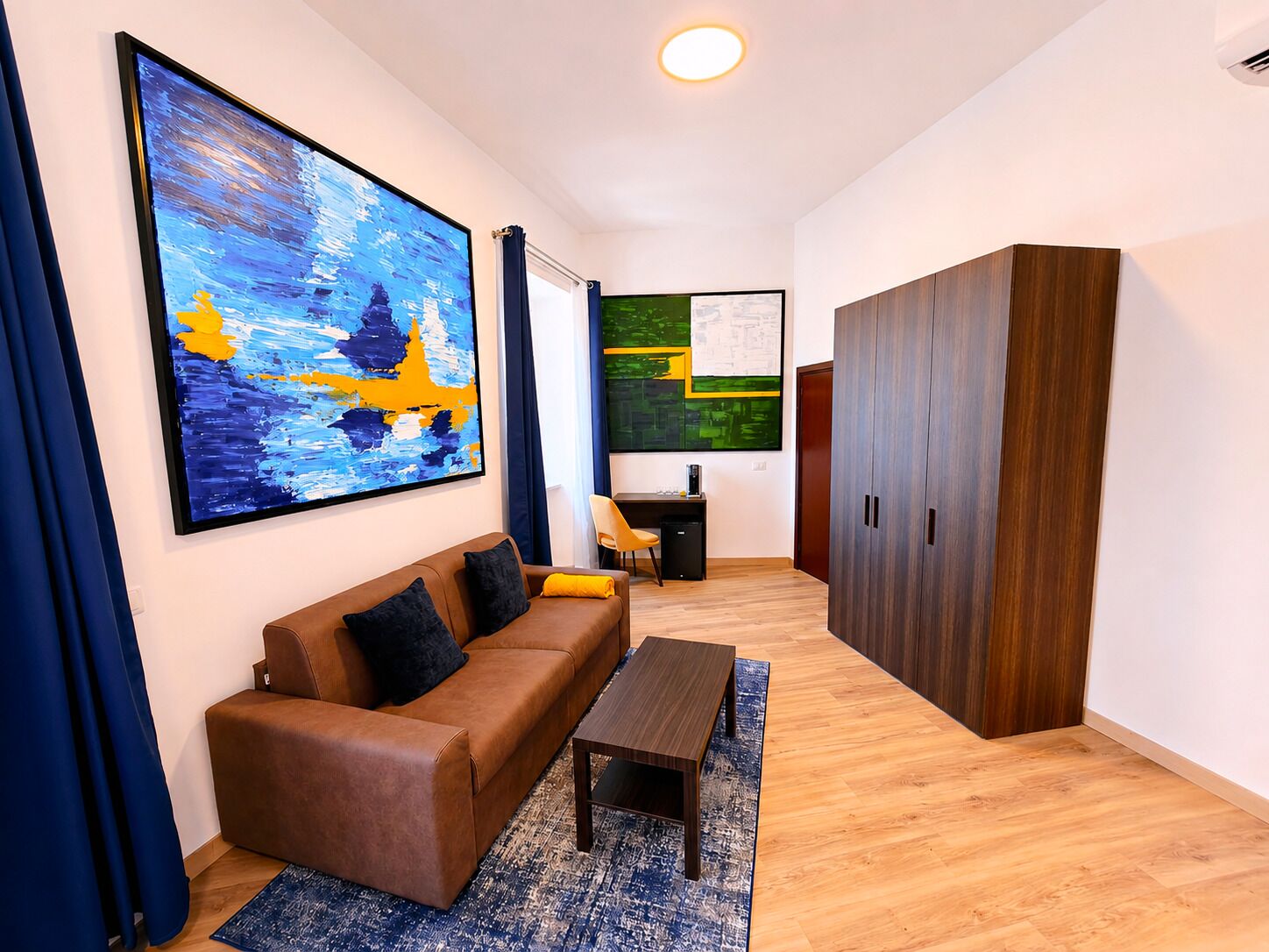 A modern living room with a brown sofa, a coffee table, and artwork on the walls.