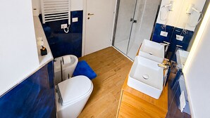 A compact bathroom with a toilet, bidet, and a shower area.