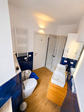 Ein kleines Badezimmer mit Toilette, Bidet und Duschbereich.