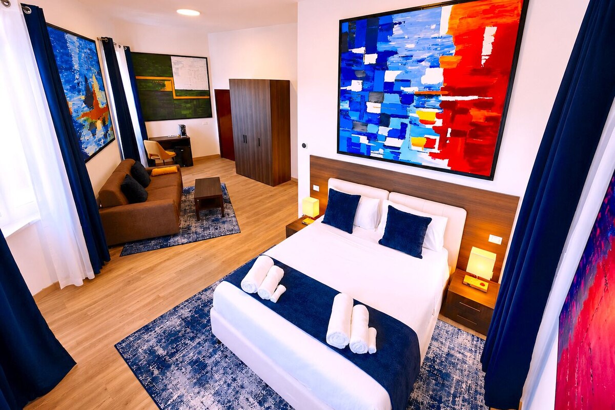 Una habitación de hotel moderna con una cama grande, un sofá, un escritorio y un armario.