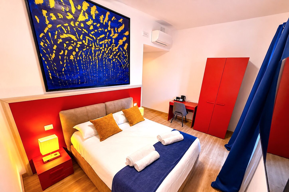 Habitación de hotel con cama, escritorio, armario y un cuadro en la pared.