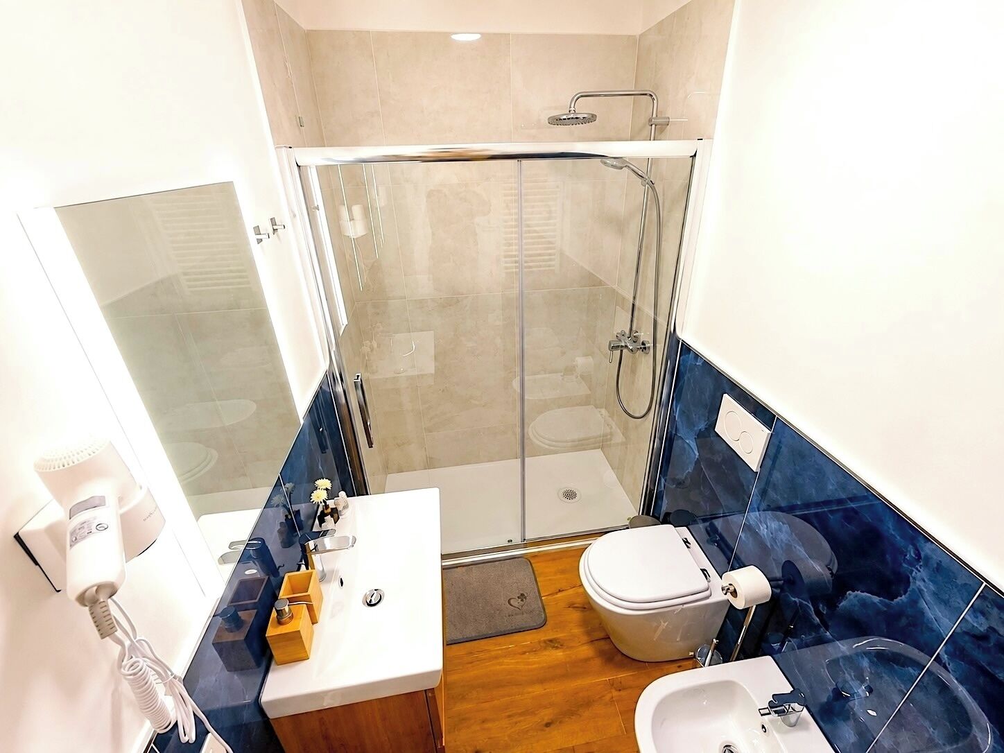 Une salle de bain moderne dotée d’une douche à parois de verre, de toilettes, d’un lavabo et d’un bidet.