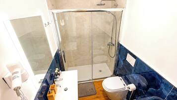 Une salle de bain moderne dotée d’une douche à parois de verre, de toilettes, d’un lavabo et d’un bidet.