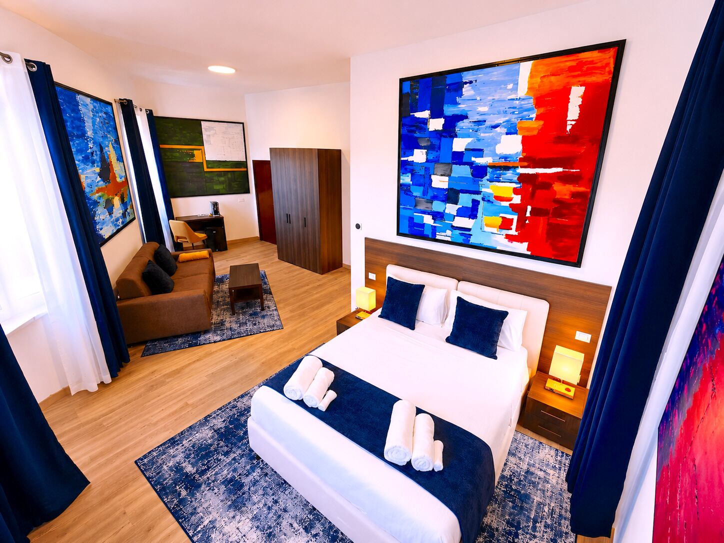 Ein modernes Hotelzimmer mit einem großen Bett, einer Couch, einem Schreibtisch und einem Kleiderschrank.