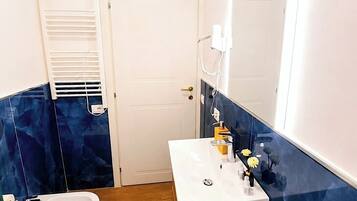 Une salle de bain avec un lavabo blanc, des toilettes et un bidet.