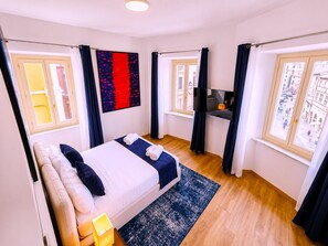 Una camera d'albergo con un letto, una televisione e vista sulla città.