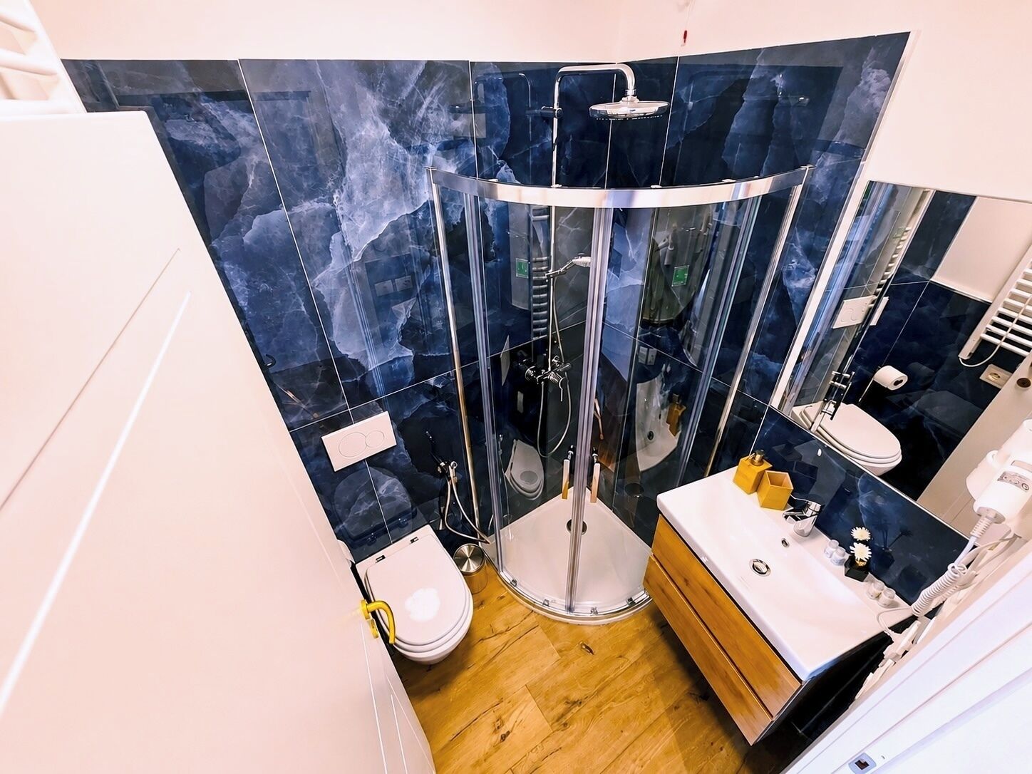 A modern bathroom with a glass-enclosed shower, a toilet, and a vanity with a mirror.