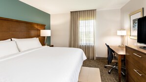 A hotel room with a large bed, a desk, a chair, a television, and a window with curtains. - ADA 2BR Suite w/ Accessible Tub | Free Breakfast! (Davie)