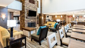 Een hotel lobby met een stenen openhaard, een zithoek en een bar.