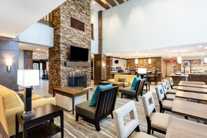 Eine Hotelhalle mit Kamin, Sitzgruppe und Bar.
