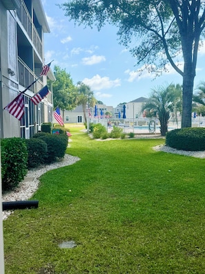 A well-maintained lawn, American flags, and a pool area with umbrellas. - Surfside Beach "Salty Sunrise" (Surfside Beach)