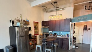 A modern kitchen with a central island, stainless steel appliances, and a dining area with stools. - Brooklyn Loft with 8 ft pool table, king sized bed, full wall of windows and AC! (brooklyn)