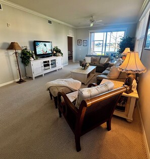 Ein Wohnzimmer mit Fernseher, Sofa, Sessel, Couchtisch und einer Lampe.