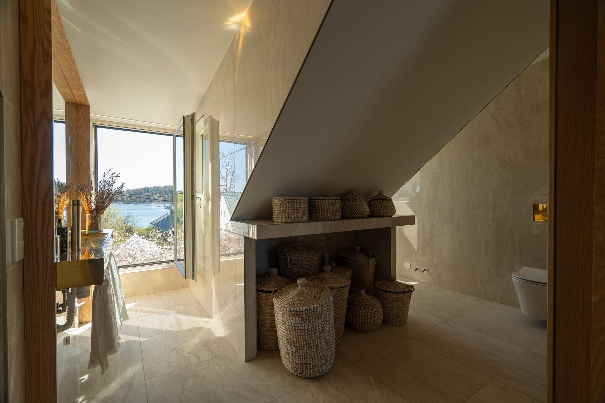 Une salle de bain moderne avec une grande fenêtre, une étagère intégrée avec des paniers et des toilettes.