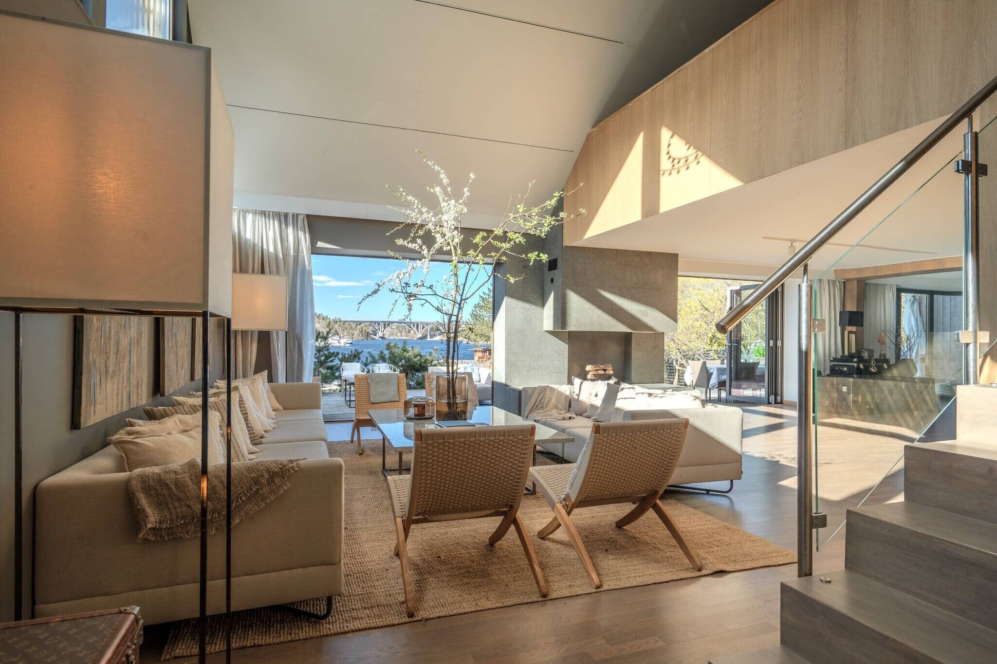 Un salon moderne avec un canapé, des fauteuils, une table basse et une vue sur l’extérieur.