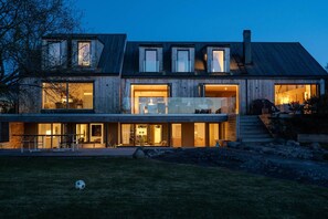 A modern two-story house with large windows, a visible outdoor area, and a staircase leading to the upper level.