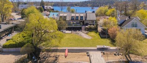 Une maison moderne dotée d’une grande terrasse offrant une vue sur une rivière, entourée d’arbres et bénéficiant d’une vue dégagée sur un lac.