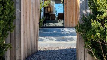 Une entrée en bois avec des marches menant à un bâtiment moderne, entouré de rochers et de verdure.