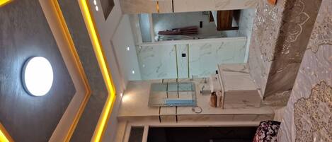 A modern kitchen with a marble countertop, a hanging rack, and a built-in oven.
