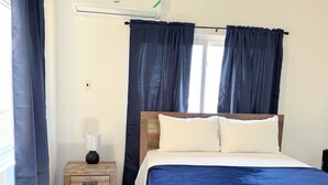 Une chambre à coucher avec un lit, une table de chevet et des rideaux.