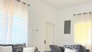 Un salon moderne avec deux canapés gris, un ventilateur de plafond et un parquet de couleur claire.