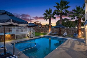 Ein Garten mit Swimmingpool, Liegestühlen und Whirlpool.