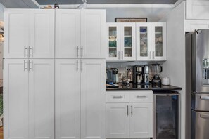 Eine Küche mit weißen Schränken, einem Edelstahl-Kühlschrank und einer Kaffeemaschine.