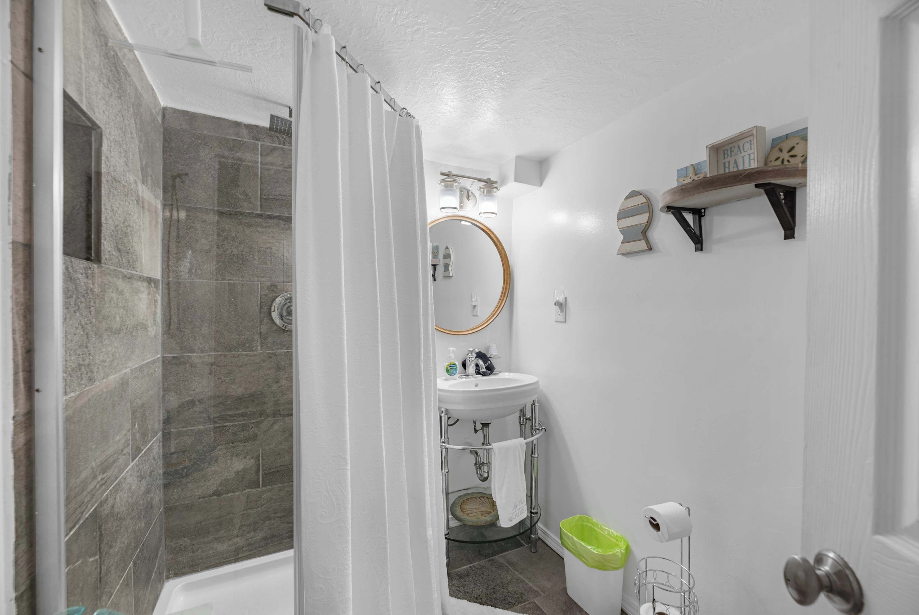 A bathroom with a shower, a sink, a toilet, and a mirror.
