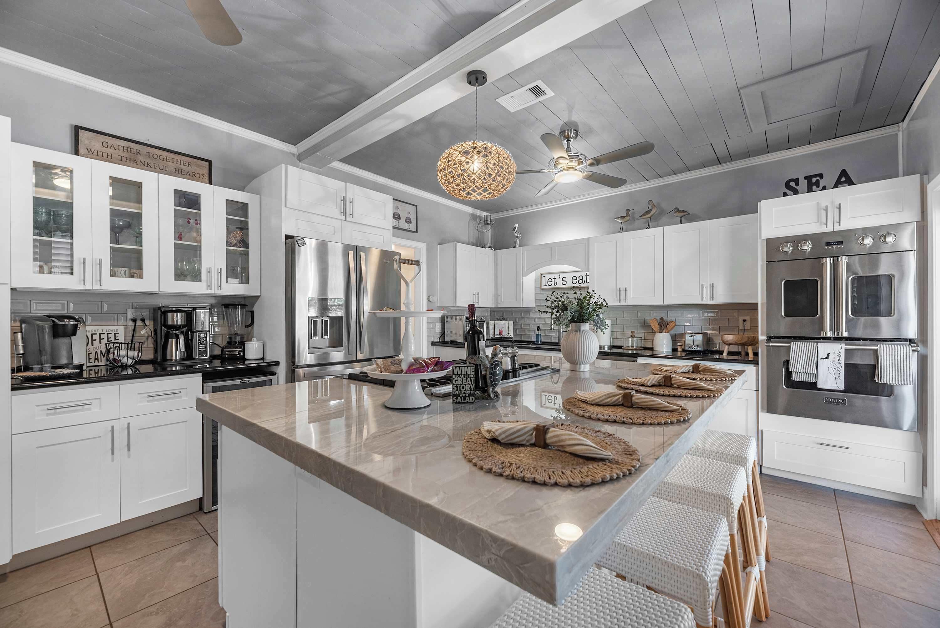 A modern kitchen with white cabinetry, stainless steel appliances, and a central island with seating.