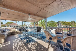 Eine überdachte Terrasse im Freien mit Deckenventilator, Esstisch mit Stühlen und einer Couch.