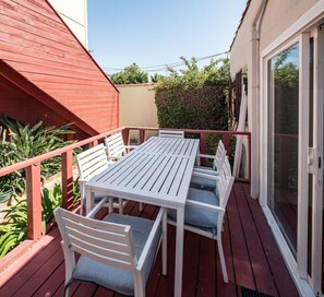 Eine überdachte Terrasse im Freien mit Tisch und Stühlen, ein rotes Dach und eine Schiebetür.