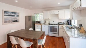A modern kitchen with white cabinets, a wooden dining table, and a view of a lake. - Bright 3 bedroom Venice House, Short Walk to Beach (Los Angeles)