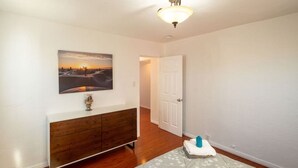 A bedroom with a bed, a dresser, a painting, and a door. - Bright 3 bedroom Venice House, Short Walk to Beach (Los Angeles)