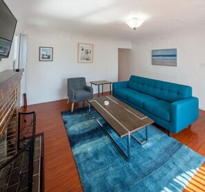 Ein Wohnzimmer mit Sofa, Couchtisch, Sessel und Kamin.