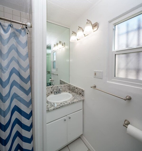 A bathroom with a white sink, a mirror, a shower curtain, and a window. - Bright 3 bedroom Venice House, Short Walk to Beach (Los Angeles)