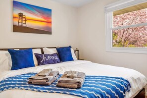 A hotel room with a bed, pillows, a blanket, and a painting of a sunset. - Downtown Oasis! Hot Tub, 2 King Beds, Garage Parking, Huge Private Yard! (Milwaukee)