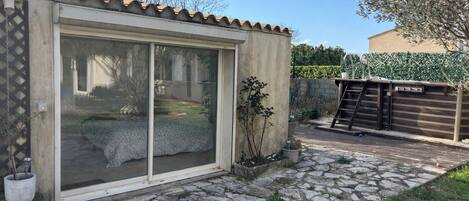 A building with a large sliding glass door, a stone-paved patio, and a wooden fence.
