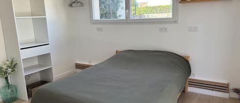 Une chambre à coucher avec un lit, une armoire, une fenêtre et une étagère.