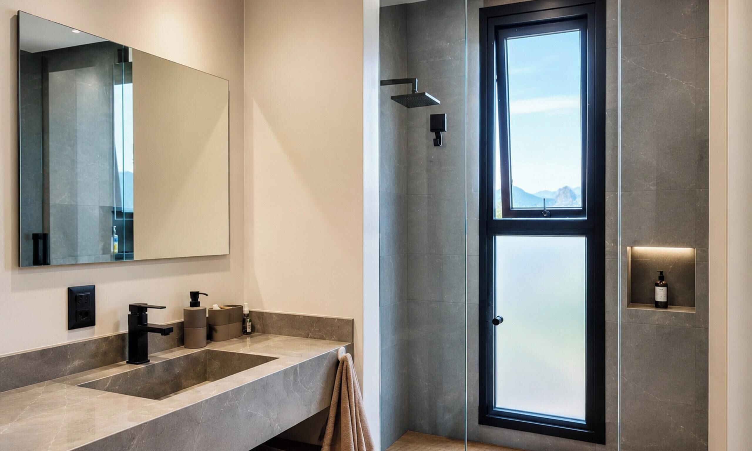 A modern bathroom with a large mirror, a shower with a glass door, and a sink with a marble countertop.