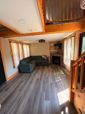 Ein geräumiger Wohnbereich mit Ecksofa, Kamin und einer Holztreppe.
