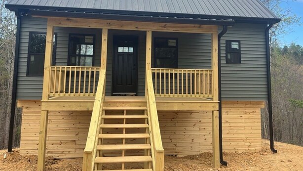 A two-story building with a front porch, a staircase, and a metal roof. - Bear Hollow 2-bed cabin in charming Old Fort with AC (Old Fort)