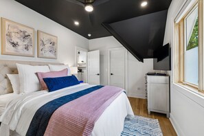 A bedroom with a bed, a TV, and artwork on the wall.