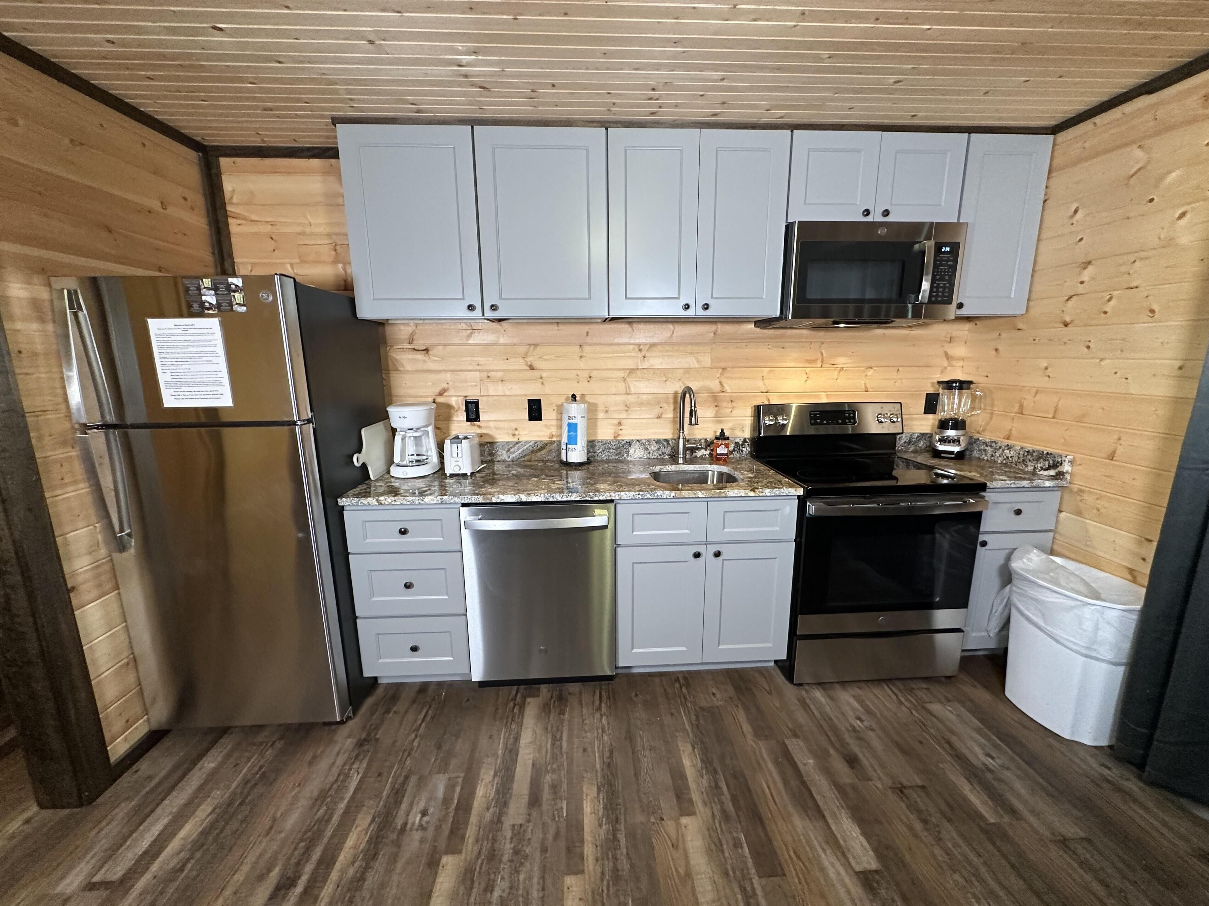 A compact kitchen with a refrigerator, microwave, stove, and sink.