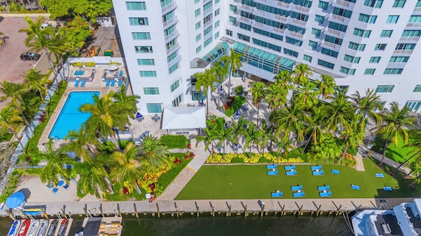 A high-rise hotel with a swimming pool, palm trees, and a marina. - Atlantic Ocean Sunrise Suite Unit 820 (Fort Lauderdale)