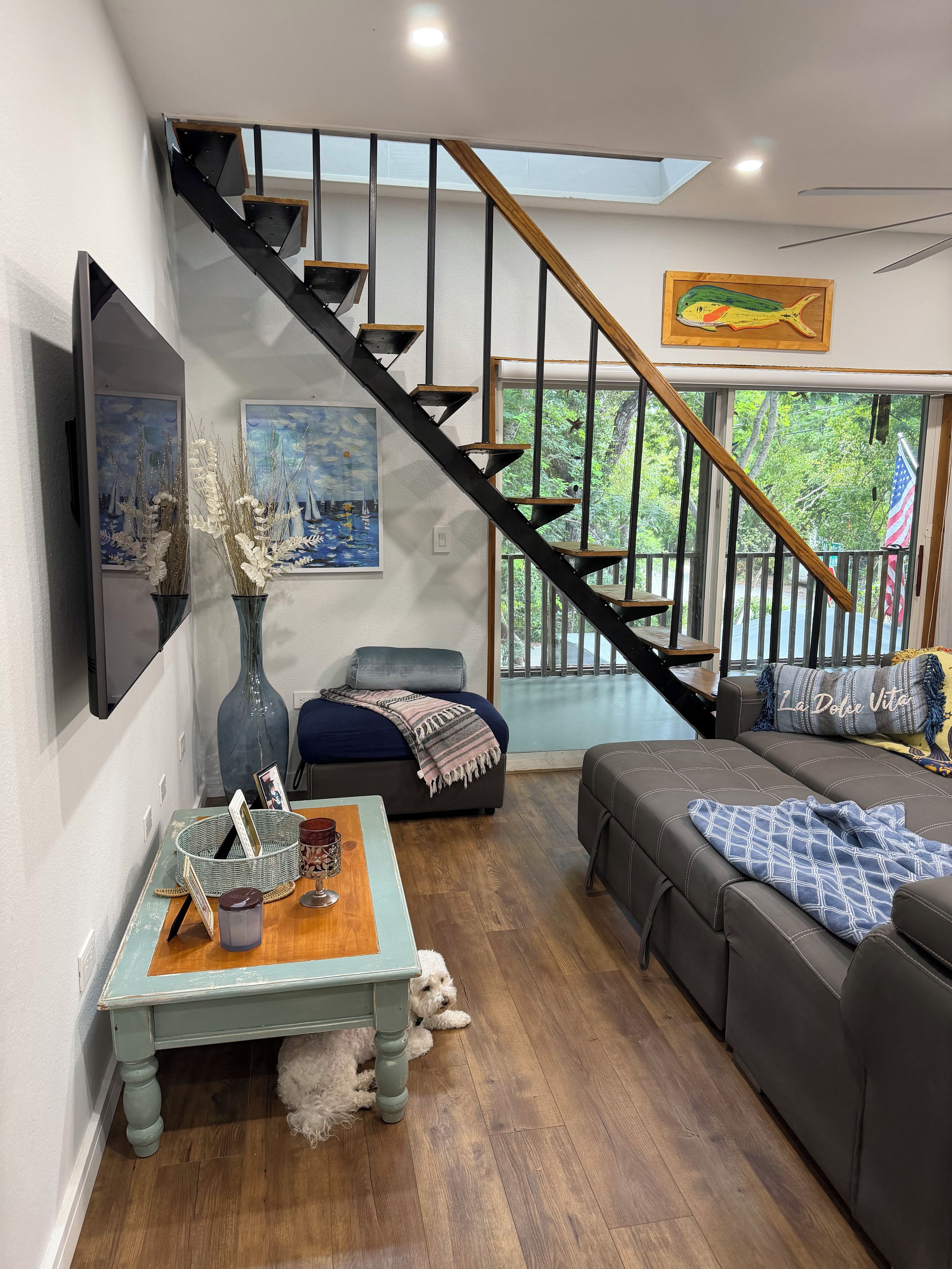 A modern living room with a staircase, a sofa, a coffee table, and a dog.