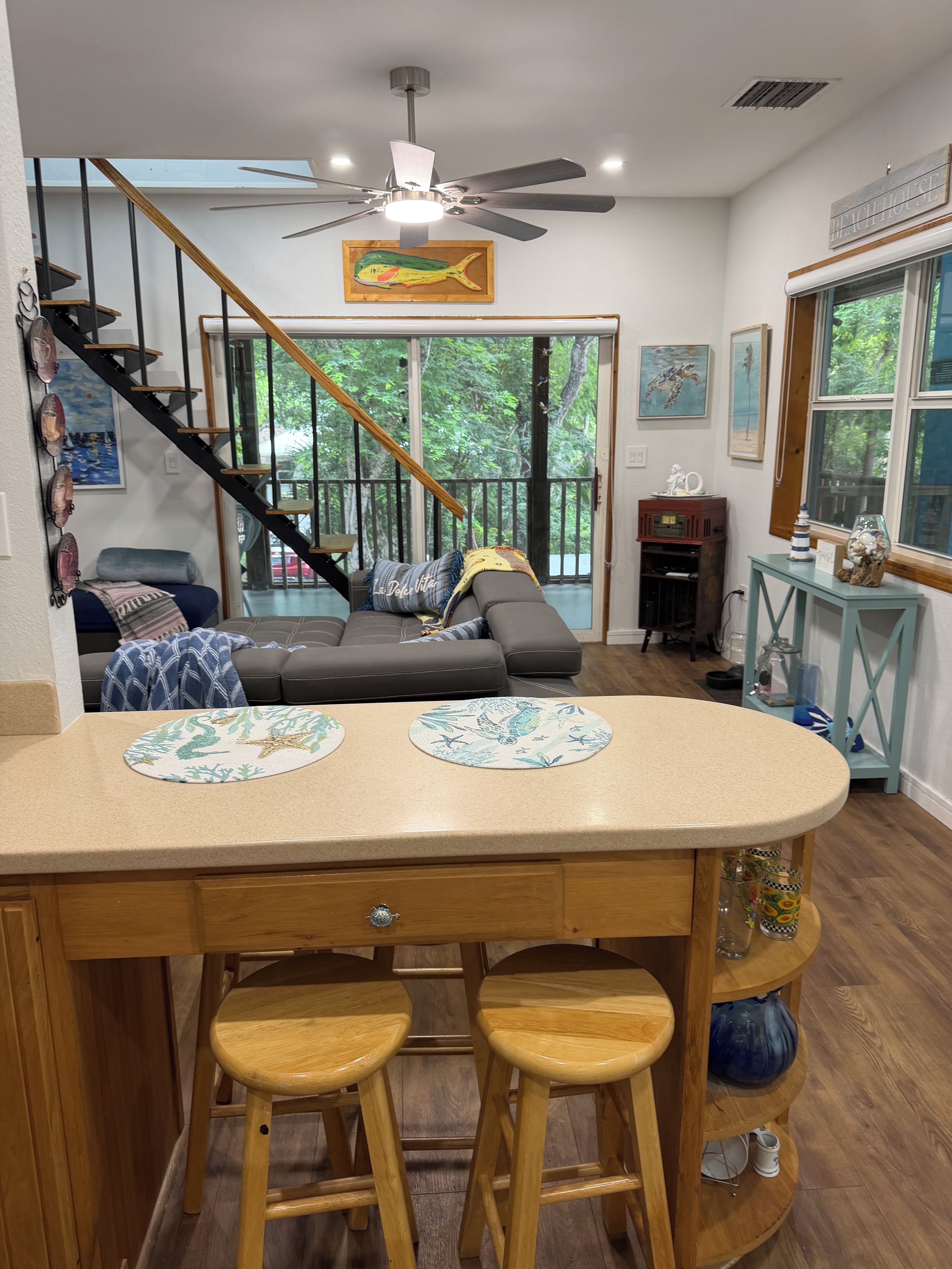 A kitchen with a central island, stools, and a staircase leading to a balcony.